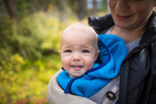 Portrait of mother holding baby in a front carrier.