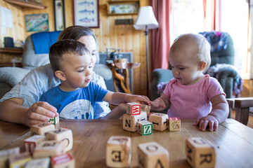 Mother helping her two children play nicely together.