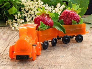 Children's toy locomotive carries strawberries in wagons