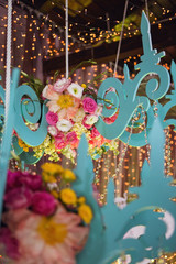 Decorative chandelier decorated with fresh flowers on the background of glowing light bulbs. Decor for the holiday in the restaurant.