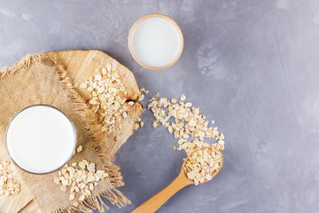Oat milk. Organic oat milk on a wooden stand. Vegan non-dairy organic drink with oat flakes....