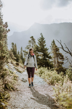 woman wearing white coat hikes on trail in glacier park montana