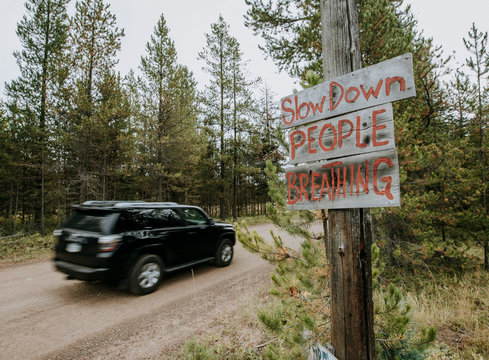 a sign on a dirt road with speeding car warning drivers to slow down