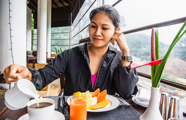 woman pouring milk into her coffee at breakfast