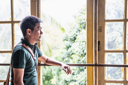 portrait of a Thai man standing in front of an open window