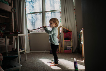 toddler in bedroom playing toy trumpet