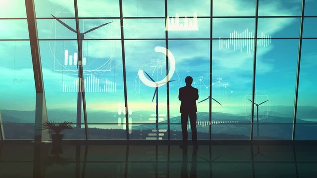 Silhouette of a man standing in his office on the background of wind power stations and infographics.