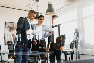 Diverse team of skilled students together solving task writing down information on papers glued on wall.Multicultural young people collaborating on business plan making notes of ideas on sticker