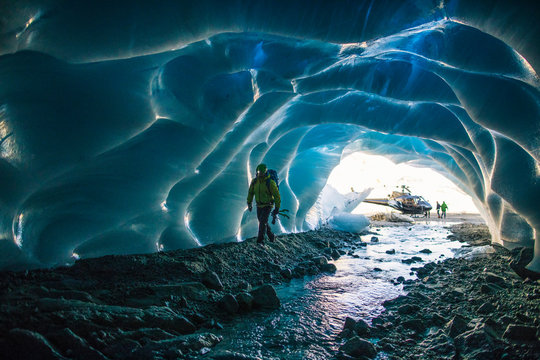Ice climber enters ice cave to find a climbing route. - Powered by Adobe