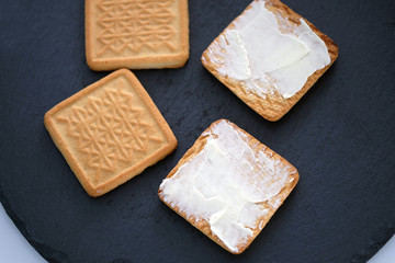 Baked milk cookies with butter top view. Shortbread cookies with butter on a black board. Tasty dessert for coffee.