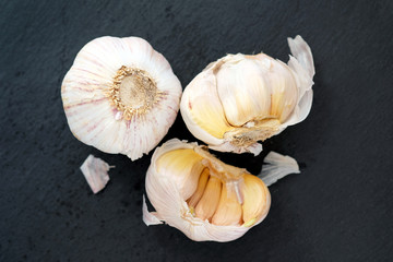 Garlic on a black background top view. Two heads of garlic, one whole, the other divided in half. Dry garlic with yellow edges.