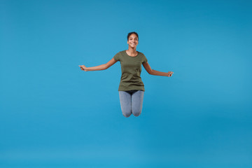 Obraz premium Smiling young african american woman girl in casual clothes posing isolated on bright blue background studio portrait. People emotions lifestyle concept. Mock up copy space. Jumping, spreading hands.