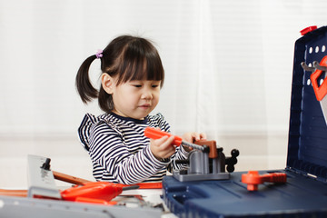 toddler girl pretend using DIY tool at home against white background
