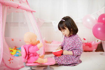 Obraz na płótnie Canvas toddler girl pretend play baby care at home against white background