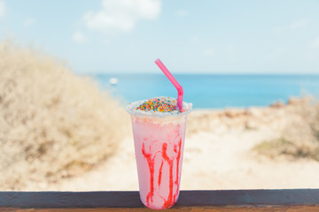 Lovely strawberry Milkshake in the hand on the beach at Cyprus, Ayia Napa, Blue lagoon. Soft colours, Summer time.