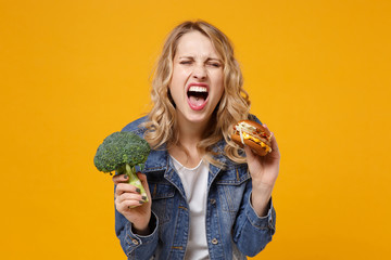 Crazy young woman in denim clothes isolated on yellow orange wall background studio portrait....