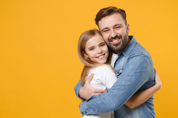 Fototapeta premium Pretty bearded man in casual clothes have fun with cute child baby girl. Father little kid daughter isolated on yellow wall background in studio. Love family day parenthood childhood concept. Hugging.