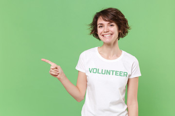 Smiling young brunette woman in white volunteer t-shirt isolated on pastel green background in...