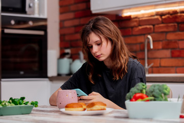 sad teen girl uses a phone in the kitchen
