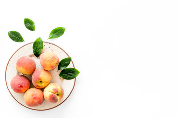 Summer fruits. Ripe red peaches on plate on white table top-down copy space