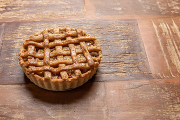 Homemade apple pie with cinnamon and a golden crust, on a wooden background