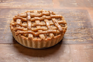 Homemade apple pie with cinnamon and a golden crust, on a wooden background