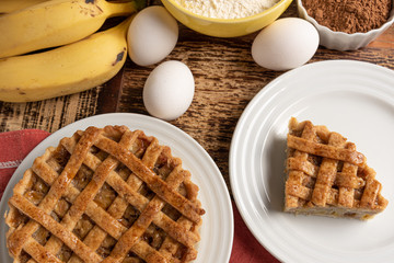 Homemade banana pie with cinnamon and a golden crust, on a wooden background