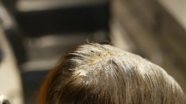 hair coloring of a young fair-haired girl at the hairdresser in a brunette
