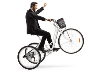 Man in a suit riding a white tricycle and gesturing happiness with hand