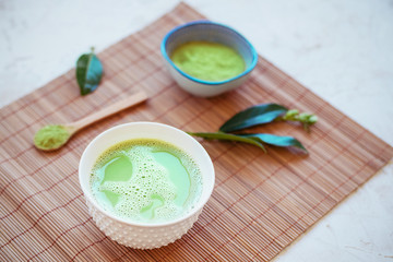 Matcha green tea in a cup on a bamboo tablecloth. Japanese tea ceremony concept. Top view, close up.