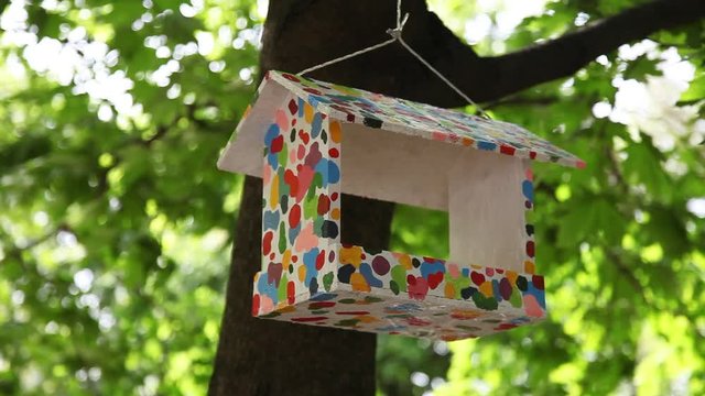 birdhouse with decoration hanging on a tree in summer garden
