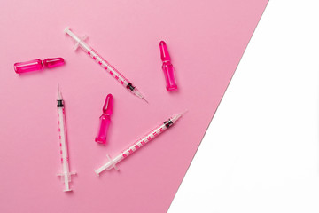 Syringes and ampules with pink liquid on isolated white and pink background. Cosmetology and medicine concept. Flat lay.