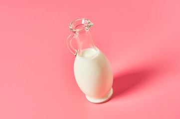 Full jug of fresh milk, yogurt or kefir on pink background