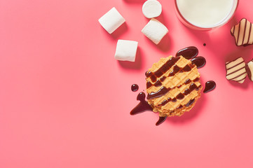 Full glass of fresh milk, yogurt or kefir near thin waffles, chocolate candies and marshmallow on...