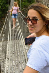 Girls on a dangerous suspension bridge over a mountain river, near Lahich
