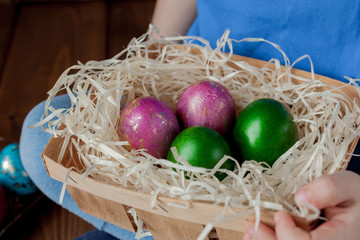 Happy baby boy with a basket of easter eggs on wooden background