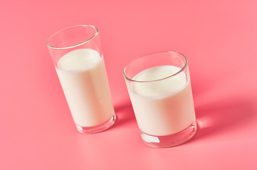 Two full glasses of fresh milk, yogurt or kefir on pink background