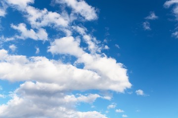 Naklejka na ściany i meble Beautiful white soft fluffy clouds on a blue sky background. Copy space