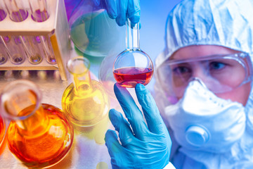 A girl in protective clothing and a mask examines the chemical liquid in the flask. Synthesis of new types of raw materials for industry. Laboratory tests of an unknown substance.