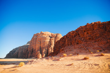 Textured sand mountains of red and orange sand against the blue sky, Jordan, Wadi Rum desert.