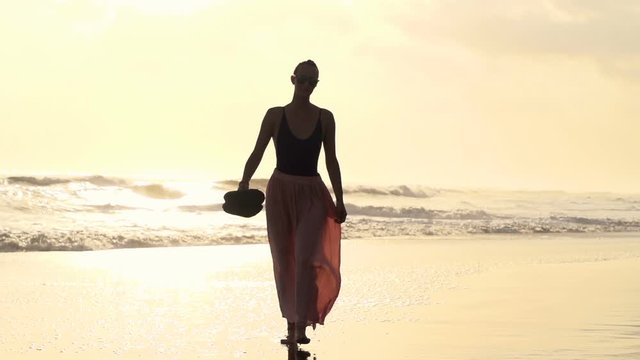 Beautiful young woman walking on the beach, super slow motion