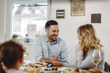 Loving couple holding hands and talking while having lunch in dining room.