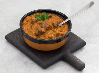Meat dish goulash of beef, stewed meat with vegetables and tomatoes in a bowl