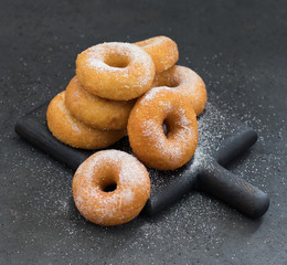 Cottage cheese donuts with powdered sugar on a dark background