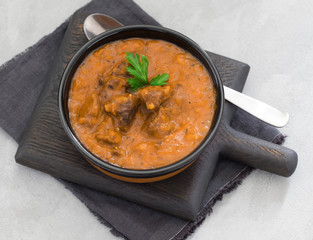 Meat dish goulash of beef, stewed meat with vegetables and tomatoes in a bowl