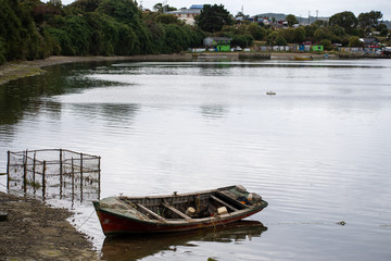 Fishing boat on water and village at background at Chiloe