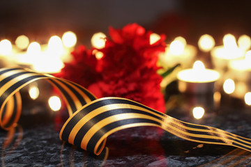 George Ribbon and carnations on the background of burning candles, candles of memory. Still life,...