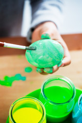 Boy paints easter eggs with a brush