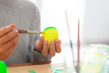 Boy paints easter eggs with a brush