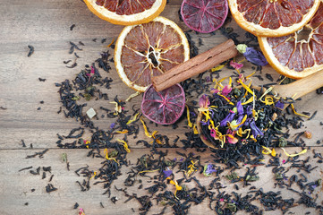 blended tea. black tea with dry flower petals and citrus fruits. dry black tea leaves in a wooden...